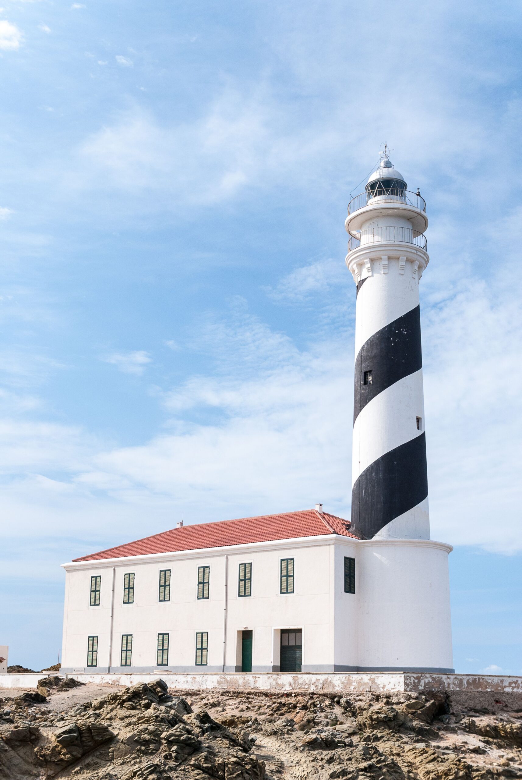 A striking view of the iconic Far de Favàritx lighthouse on a sunny day in Menorca, Spain.
