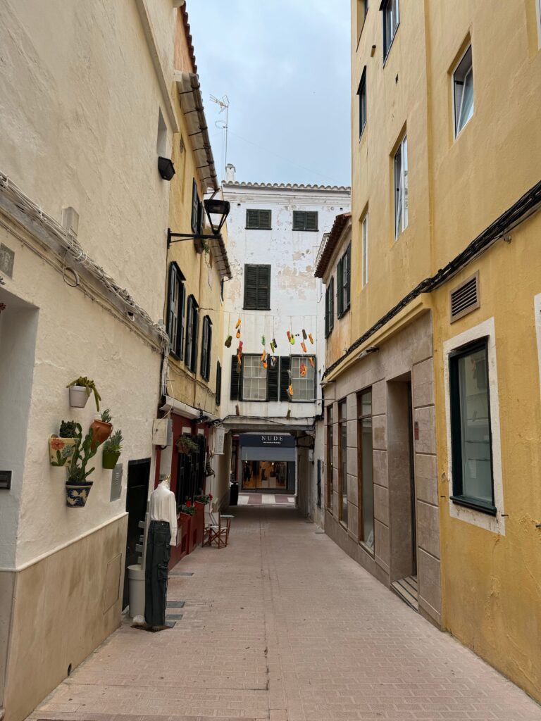Historic narrow alley with colorful flags in a sunny European city.